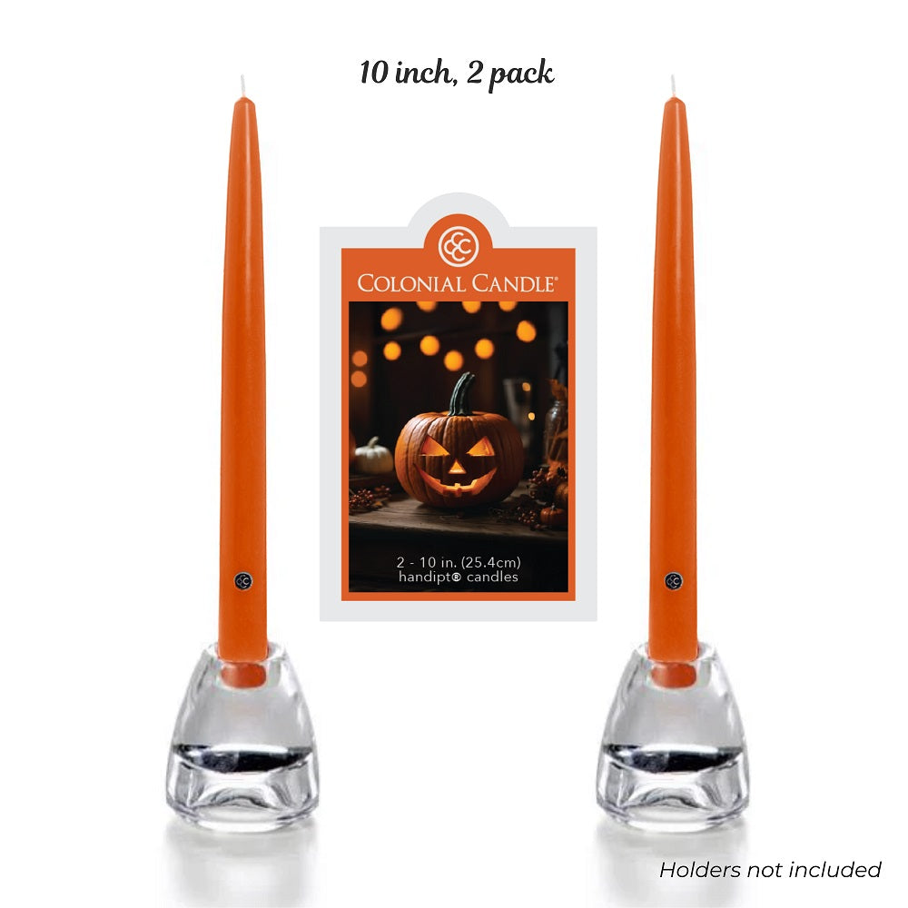 Two orange candles in holders with a Colonial Candle packaging featuring a pumpkin design on a white background.