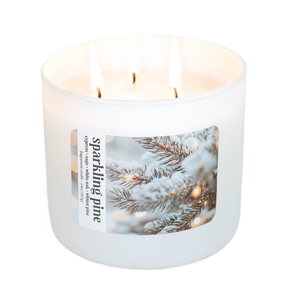Candle with a label featuring snowy pine branches on a white background