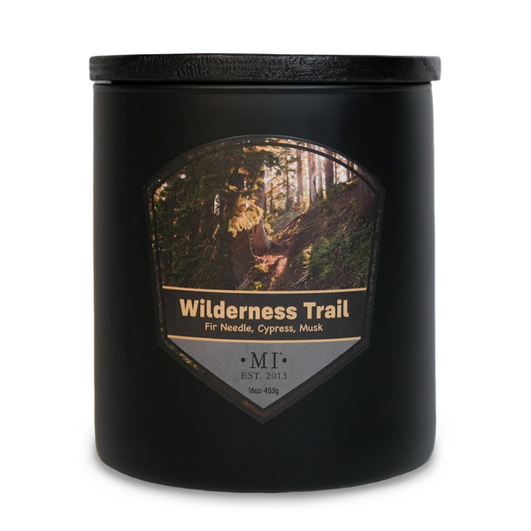 Black candle jar with 'Wilderness Trail' label featuring a forest design.