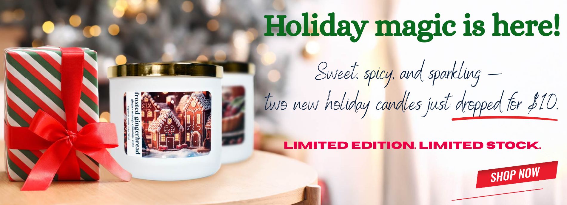 Two holiday candles with a gift box on a wooden surface, surrounded by festive lights.