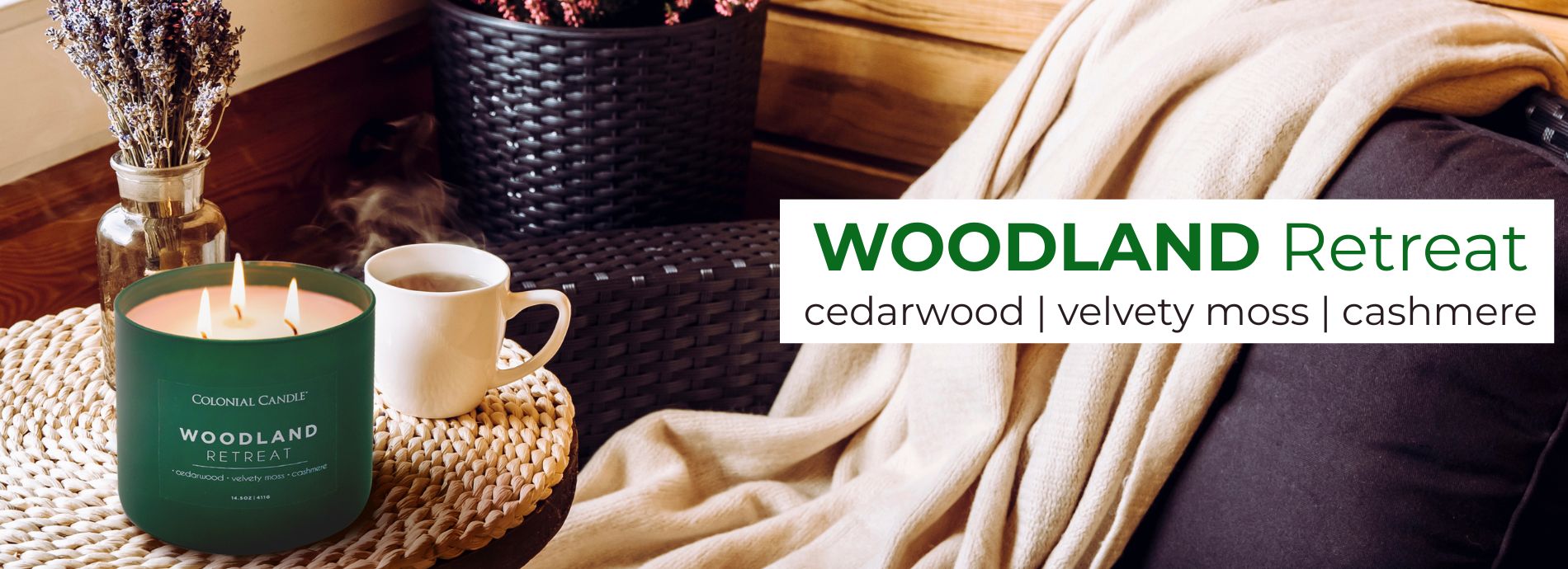 Candle labeled 'Woodland Retreat' with a cup of coffee and cozy blanket on a wooden table.